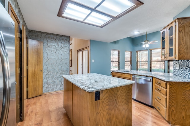 kitchen featuring a center island, light stone countertops, light wood-type flooring, and appliances with stainless steel finishes