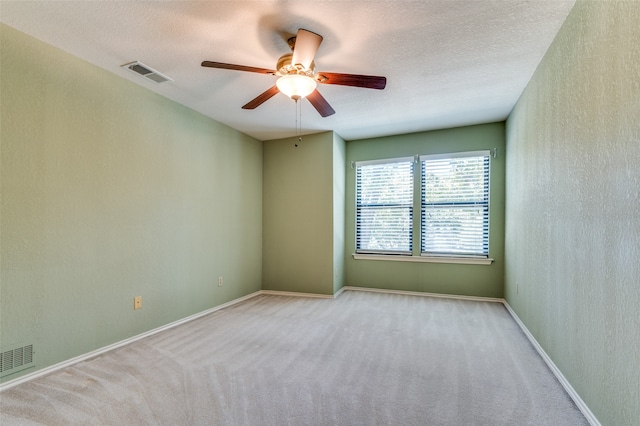 carpeted empty room with ceiling fan and a textured ceiling