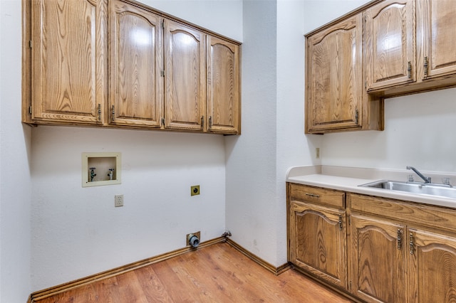 clothes washing area featuring cabinets, hookup for a washing machine, electric dryer hookup, sink, and light hardwood / wood-style flooring