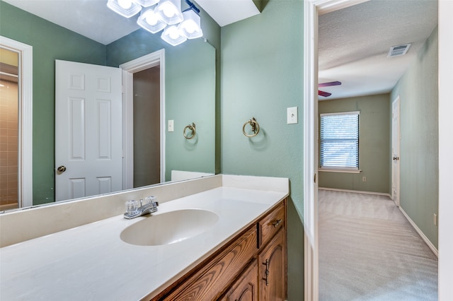 bathroom with vanity, ceiling fan, and a textured ceiling