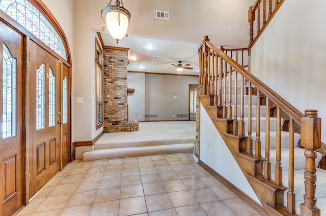 carpeted foyer entrance featuring ceiling fan and crown molding