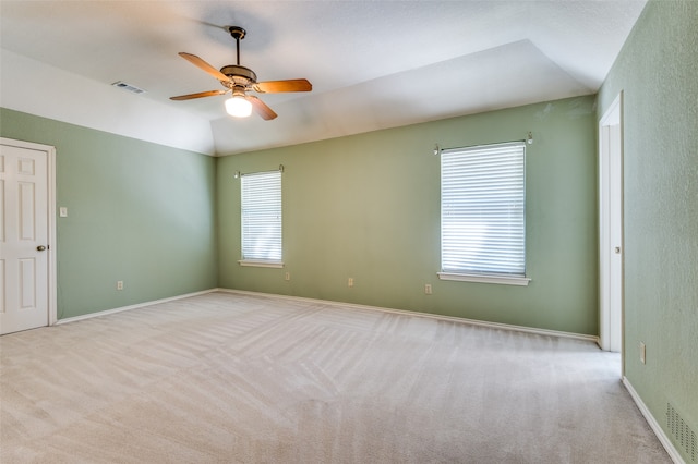 spare room featuring a wealth of natural light, ceiling fan, light carpet, and lofted ceiling