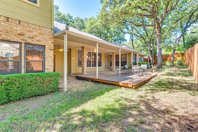 back of property featuring a yard, a deck, and ceiling fan