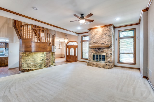 unfurnished living room with crown molding, a fireplace, carpet, and ceiling fan with notable chandelier