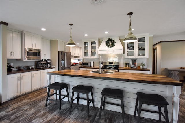 kitchen featuring premium range hood, sink, wooden counters, dark wood-type flooring, and stainless steel appliances