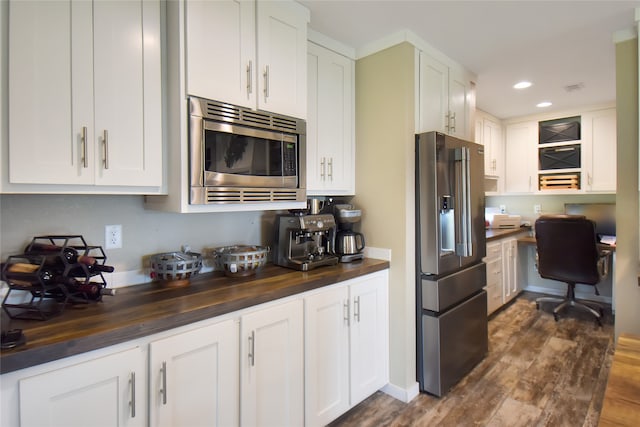 kitchen featuring white cabinets, appliances with stainless steel finishes, built in desk, and dark hardwood / wood-style flooring