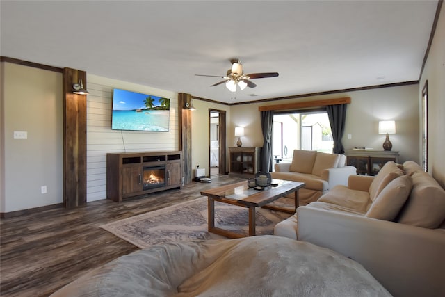 living room featuring wood-type flooring, ceiling fan, a fireplace, and crown molding