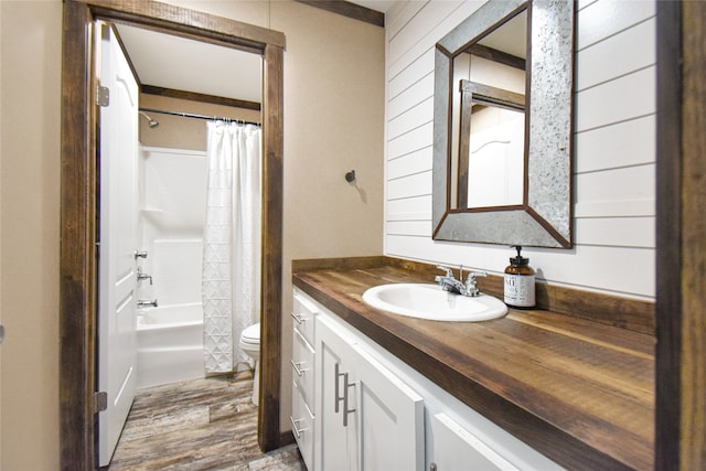 full bathroom featuring hardwood / wood-style flooring, shower / bathtub combination with curtain, wooden walls, vanity, and toilet