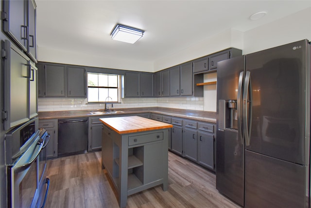 kitchen featuring black appliances, wood counters, wood-type flooring, and sink