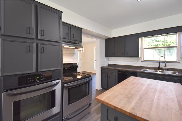 kitchen with dark wood-type flooring, sink, stainless steel appliances, backsplash, and wooden counters