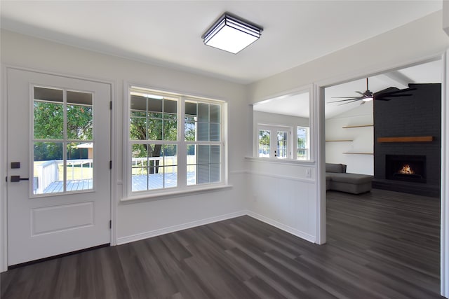 entryway featuring ceiling fan, a fireplace, lofted ceiling with beams, and dark wood-type flooring