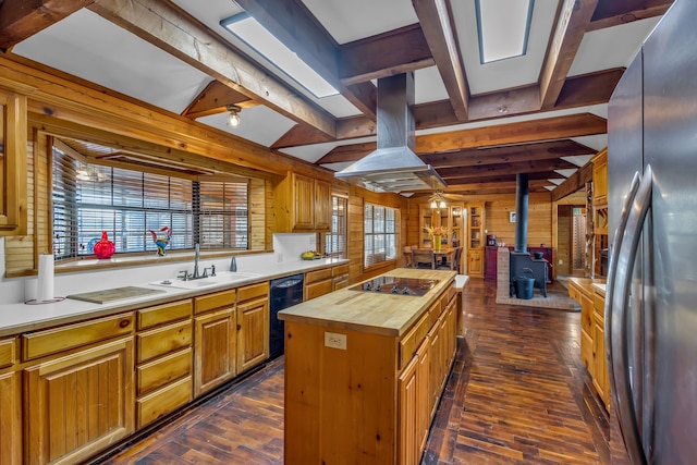 kitchen with a kitchen island, wood walls, black appliances, a wood stove, and butcher block countertops