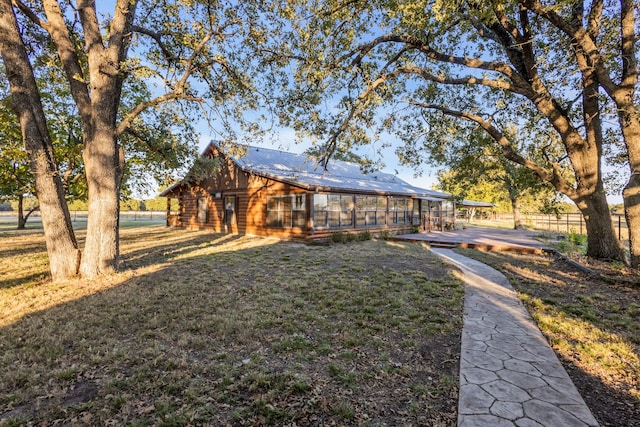 exterior space with a yard, a sunroom, metal roof, and log siding