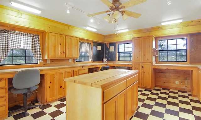 kitchen featuring butcher block countertops, a center island, wood walls, and light floors