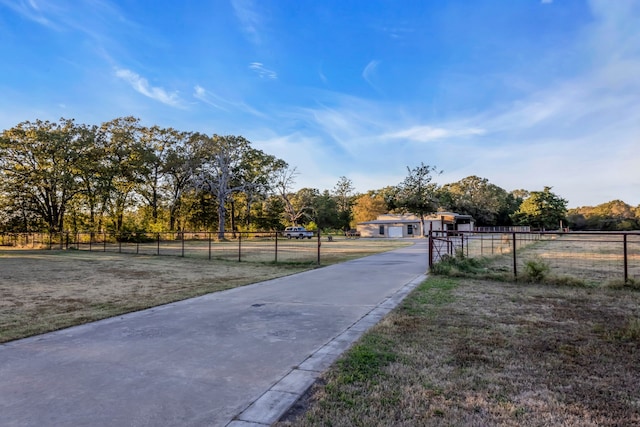 view of street featuring concrete driveway and a rural view