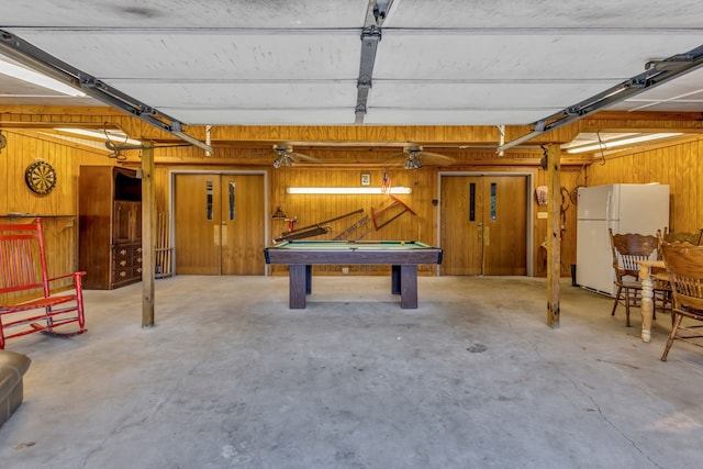 garage featuring wood walls and white fridge