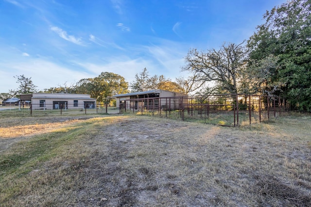 view of yard featuring an outbuilding, a rural view, fence, a pole building, and an exterior structure