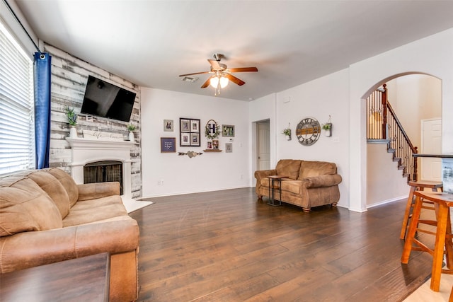 living room featuring a large fireplace, dark hardwood / wood-style flooring, ceiling fan, and plenty of natural light