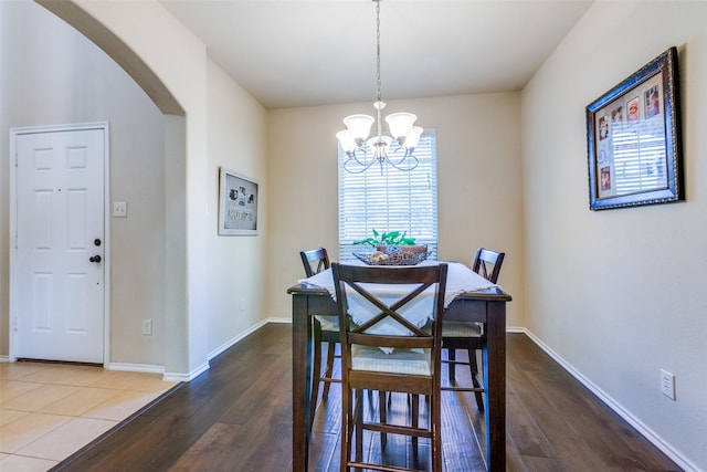 dining area with hardwood / wood-style floors and an inviting chandelier