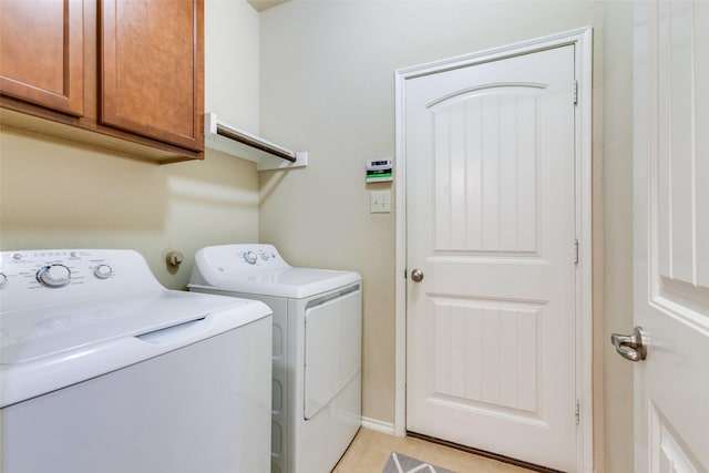 laundry room featuring washing machine and dryer, light tile patterned floors, and cabinets