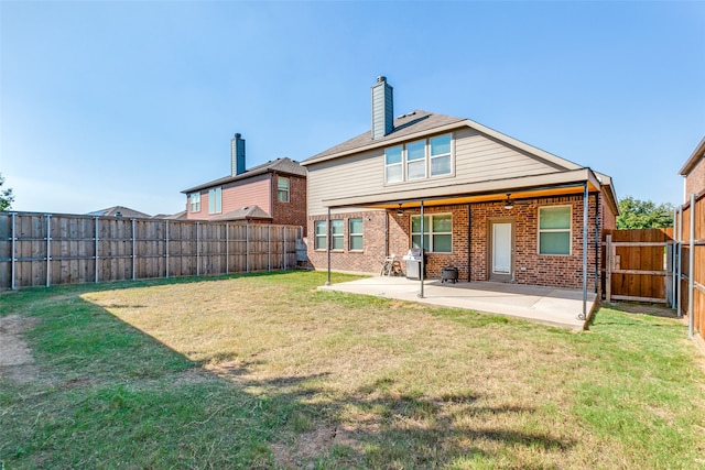 rear view of property featuring a lawn and a patio area