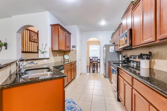 kitchen featuring light tile patterned flooring, stainless steel appliances, dark stone countertops, and sink