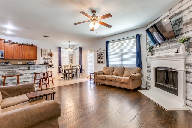 living room with dark hardwood / wood-style flooring and ceiling fan with notable chandelier