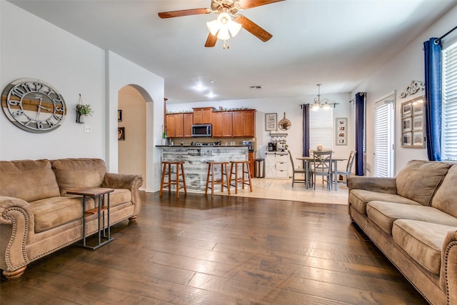 living room featuring dark wood-type flooring and ceiling fan with notable chandelier