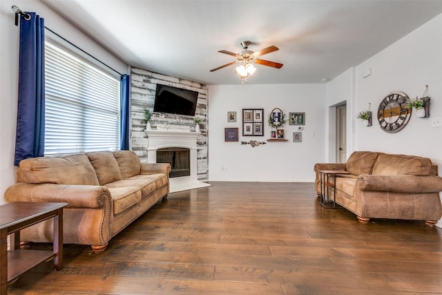 living room with a large fireplace, ceiling fan, and dark wood-type flooring