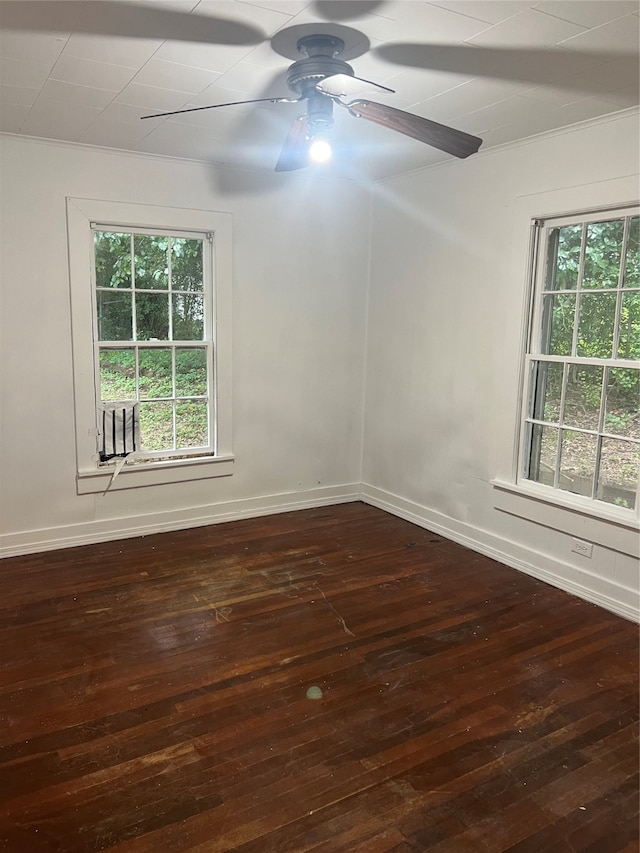 empty room featuring ornamental molding, ceiling fan, dark wood-type flooring, and plenty of natural light