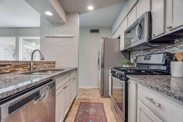 kitchen with appliances with stainless steel finishes, visible vents, a sink, and light stone counters