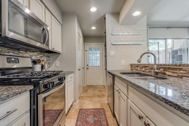 kitchen with stone counters, backsplash, appliances with stainless steel finishes, a sink, and plenty of natural light