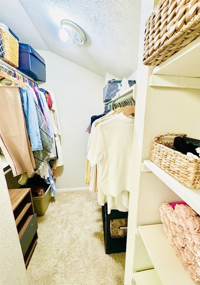 walk in closet with lofted ceiling and light carpet