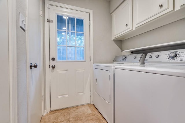 clothes washing area featuring separate washer and dryer and cabinet space