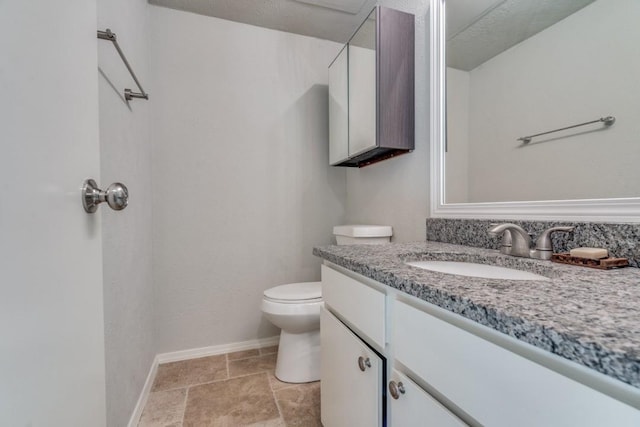 bathroom featuring toilet, baseboards, and vanity