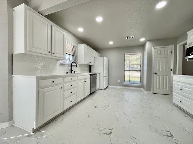 kitchen with tasteful backsplash, sink, white cabinetry, stainless steel dishwasher, and white refrigerator