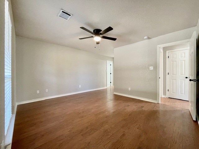 unfurnished room featuring a textured ceiling, dark wood-type flooring, and ceiling fan