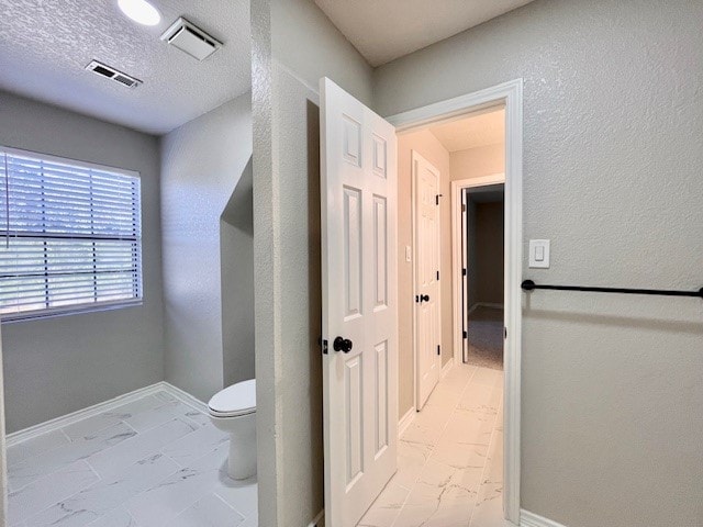 bathroom with toilet and a textured ceiling