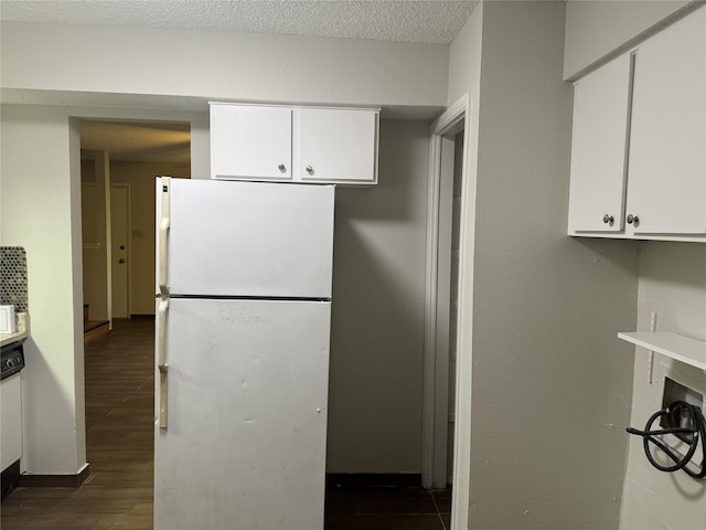 kitchen featuring a textured ceiling, dark hardwood / wood-style floors, white fridge, and white cabinetry