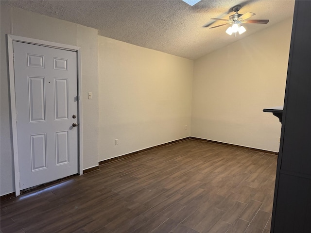 spare room featuring a textured ceiling, ceiling fan, dark wood-type flooring, and a skylight