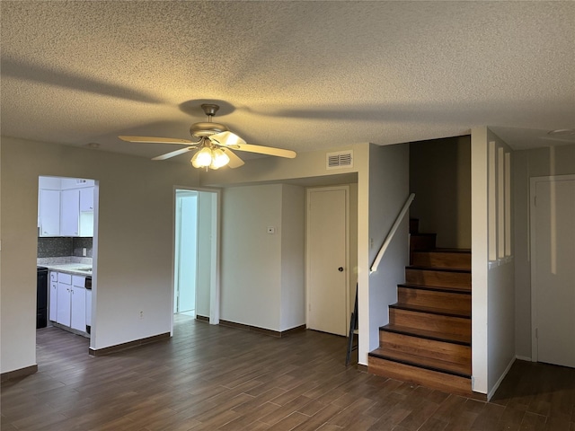 unfurnished living room featuring ceiling fan, dark hardwood / wood-style floors, and a textured ceiling