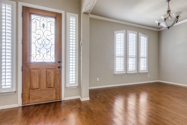 entrance foyer with dark hardwood / wood-style flooring, crown molding, plenty of natural light, and a notable chandelier