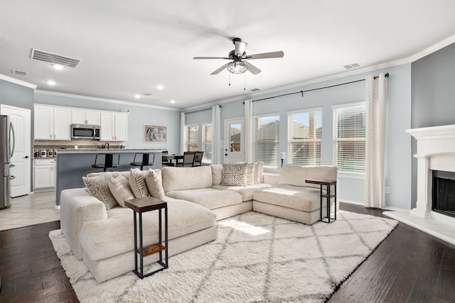 living room featuring ceiling fan, hardwood / wood-style flooring, and ornamental molding