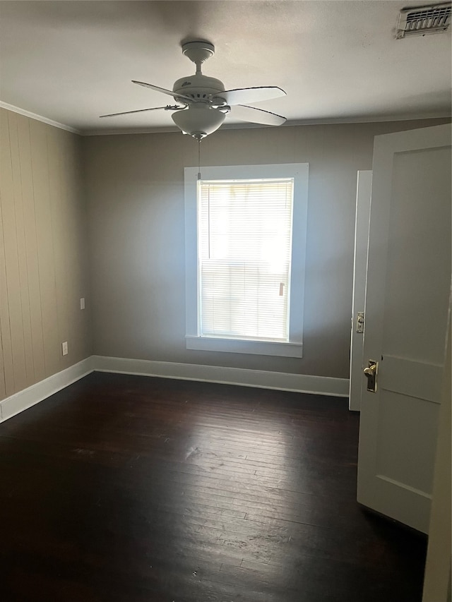 unfurnished room featuring ceiling fan, wooden walls, dark hardwood / wood-style floors, and crown molding