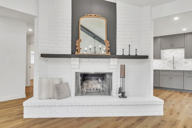 interior details with a fireplace, hardwood / wood-style floors, sink, and tasteful backsplash