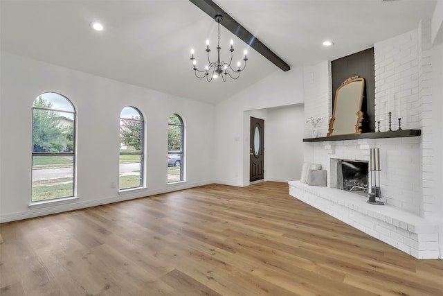 unfurnished living room with lofted ceiling with beams, light hardwood / wood-style floors, a notable chandelier, and a fireplace