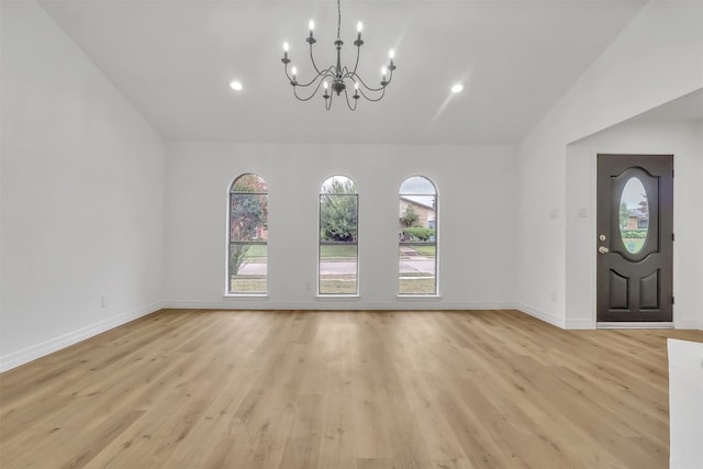 interior space featuring light wood-type flooring, vaulted ceiling, and a chandelier