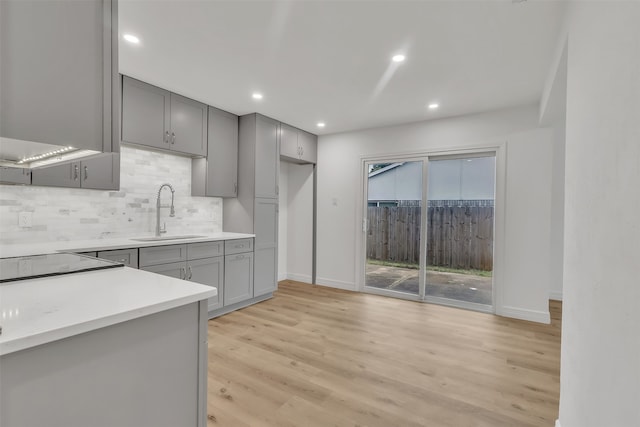 kitchen with sink, light hardwood / wood-style floors, tasteful backsplash, and gray cabinetry