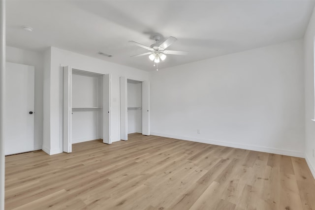 unfurnished bedroom featuring light hardwood / wood-style floors, two closets, and ceiling fan