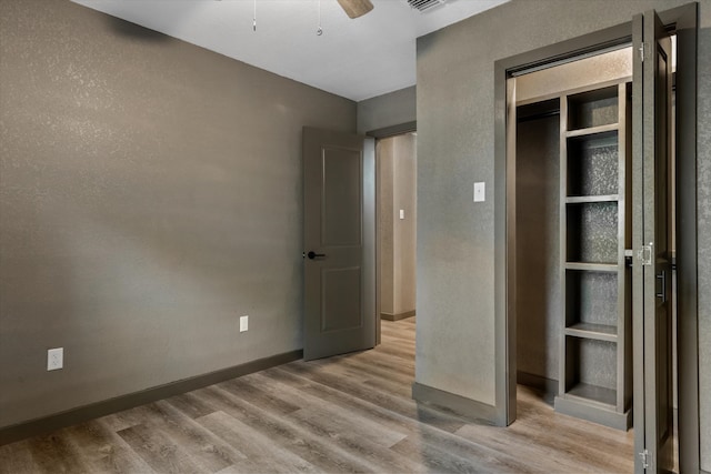 unfurnished bedroom with a closet, light hardwood / wood-style floors, and ceiling fan